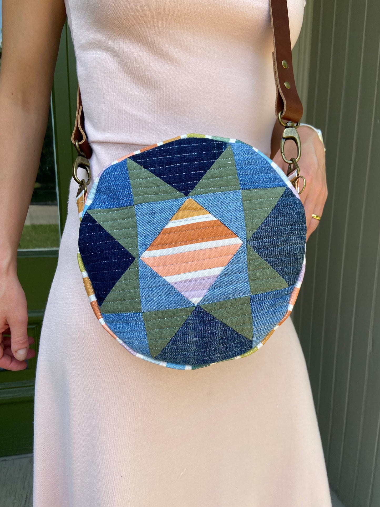 Person holding a round fabric item with a geometric pattern against a neutral background