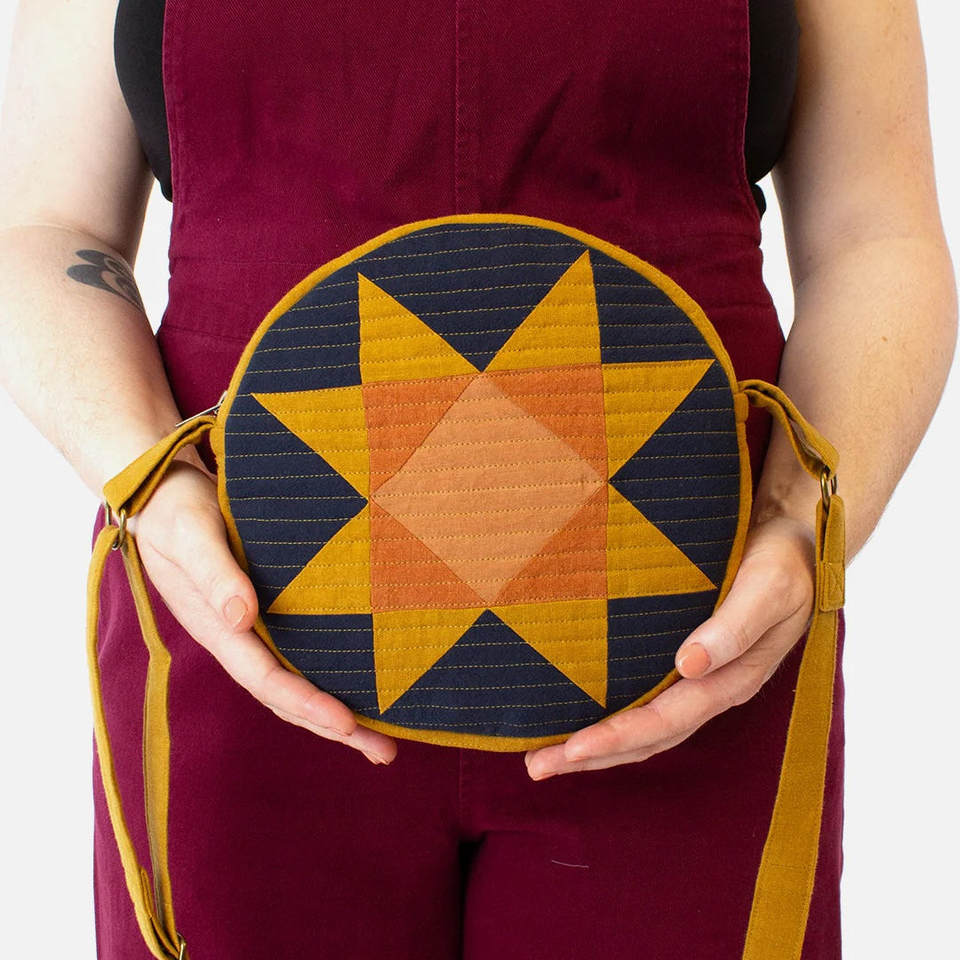 Person holding a round bag with star pattern against a white background